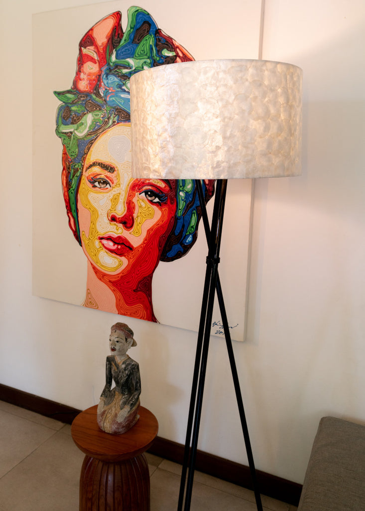 Full Shell Tripod Floor Lamp standing in front of a colorful picture