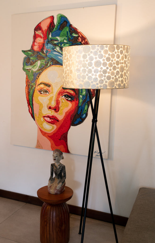 White Coin Tripod Floor Lamp with shade in front a picture. in a living room. LHD – Lighting in Singapore