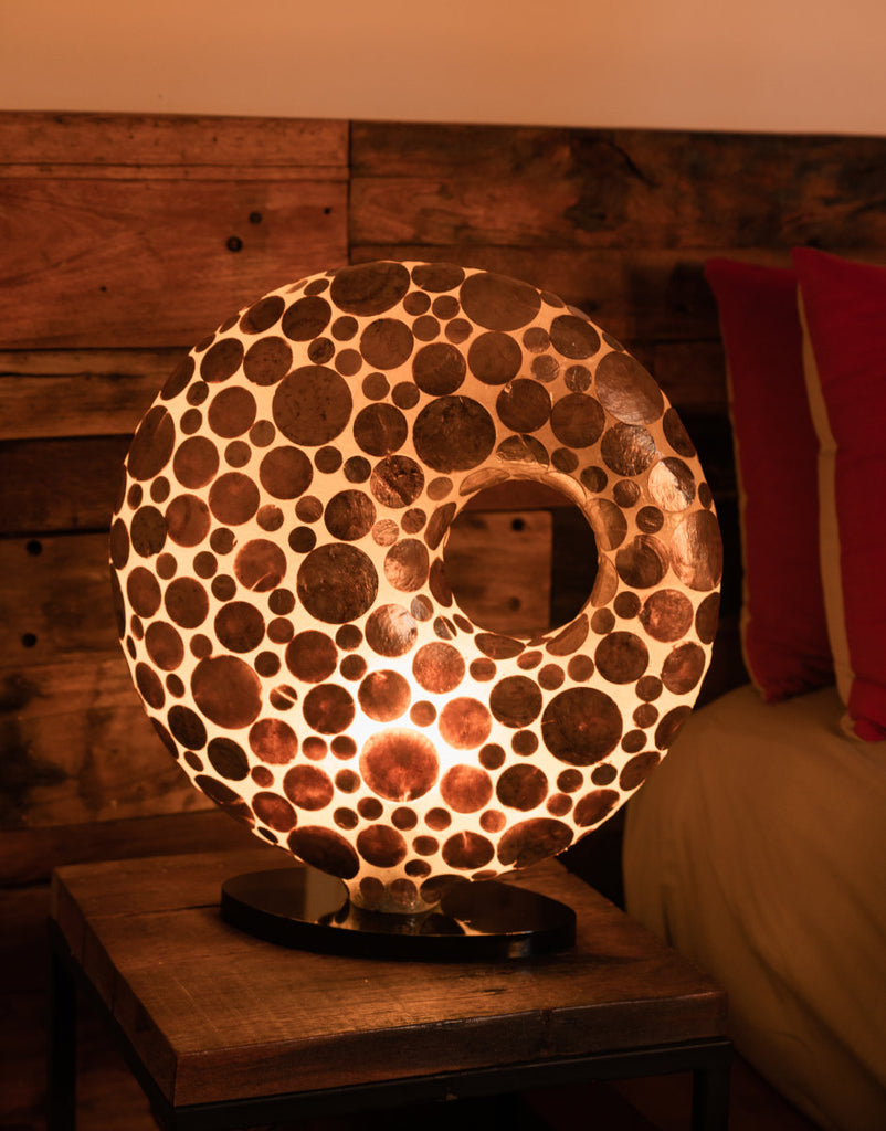 Gold Coin Doughnut shaped table lamp with very nice circles appearing on the shade when illuminated. Light House Design Lighting now available in Singapore.