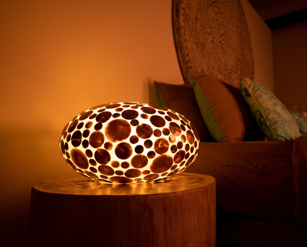 This is a Ufo Gold Coin Lamp which is used as bedside lamp in a bed room. It is glowing.