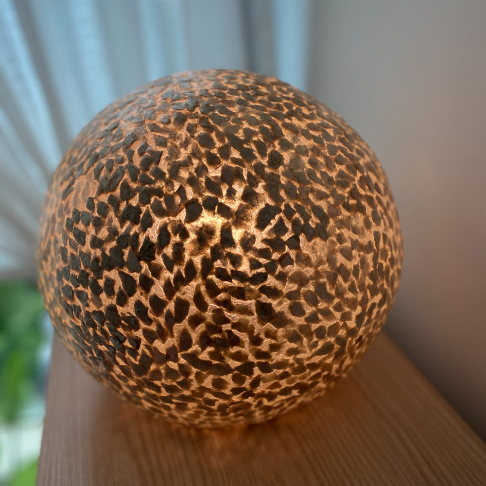 globe table lamp Wangi gold sphere standing on a cabinet in a living room in Singapore