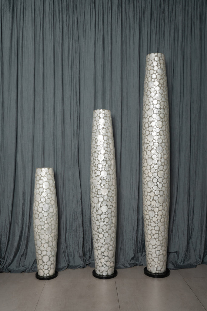 Three apollo floor lamps in different sizes infront of a curtain. 
