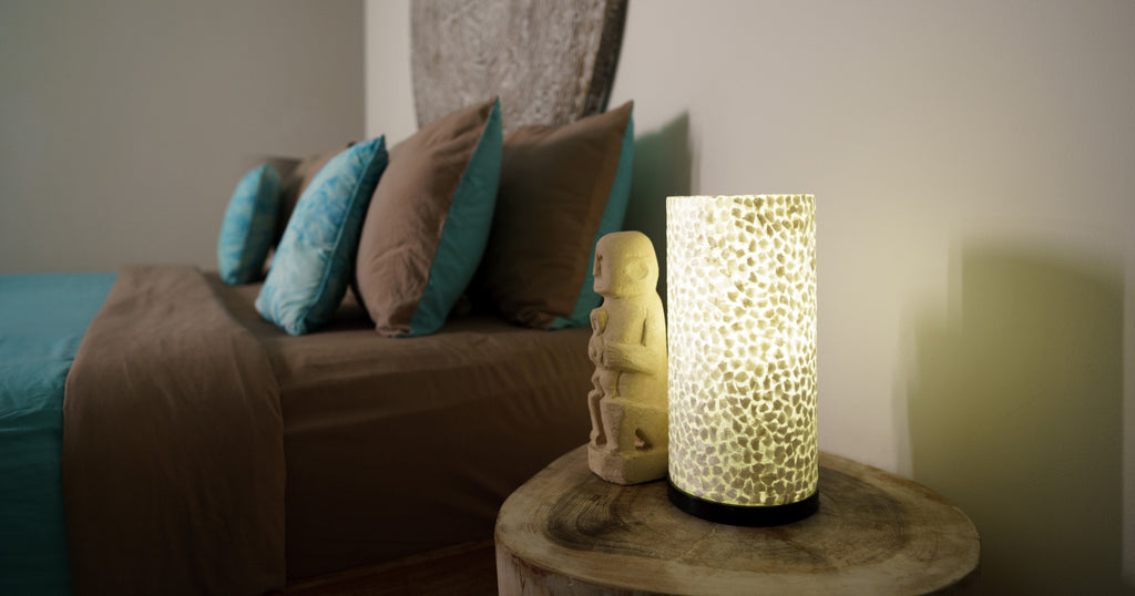 Decorative Table Lamp Wangi White on a bedside table next to a bed in a bedroom next to a small statue