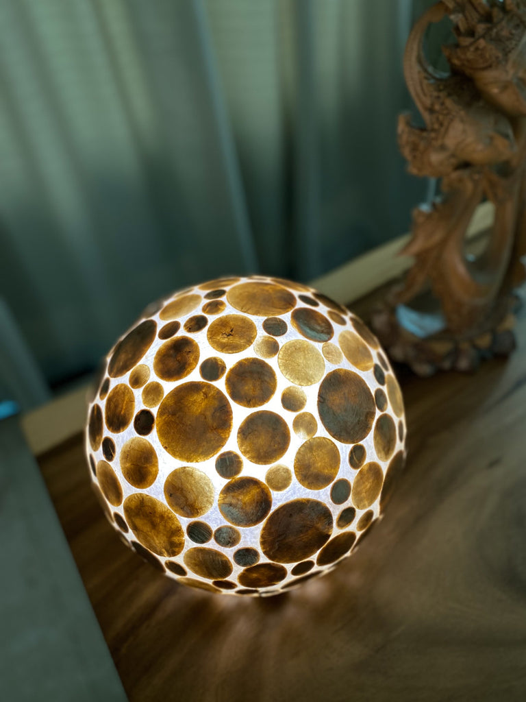 Gold Coin Globe table lamp Gold Coin Sphere on a wooden table in the dining room.