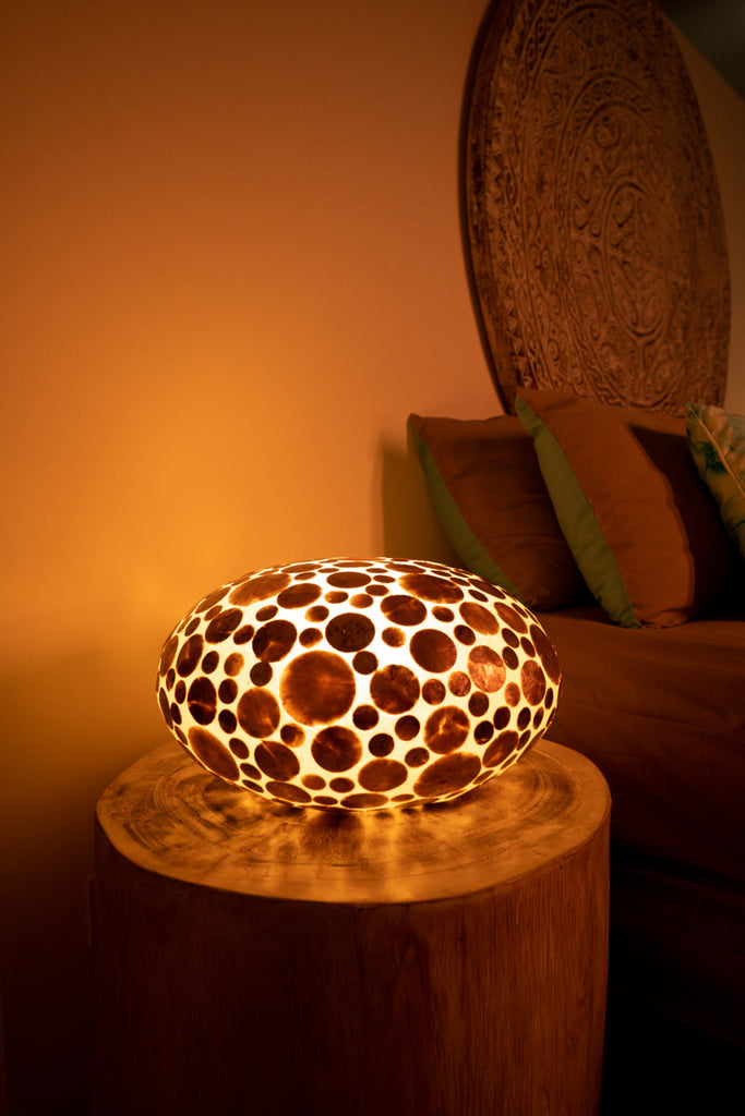 This is a Ufo Gold Coin Lamp which is used as bedside lamp in a bed room. It is glowing.