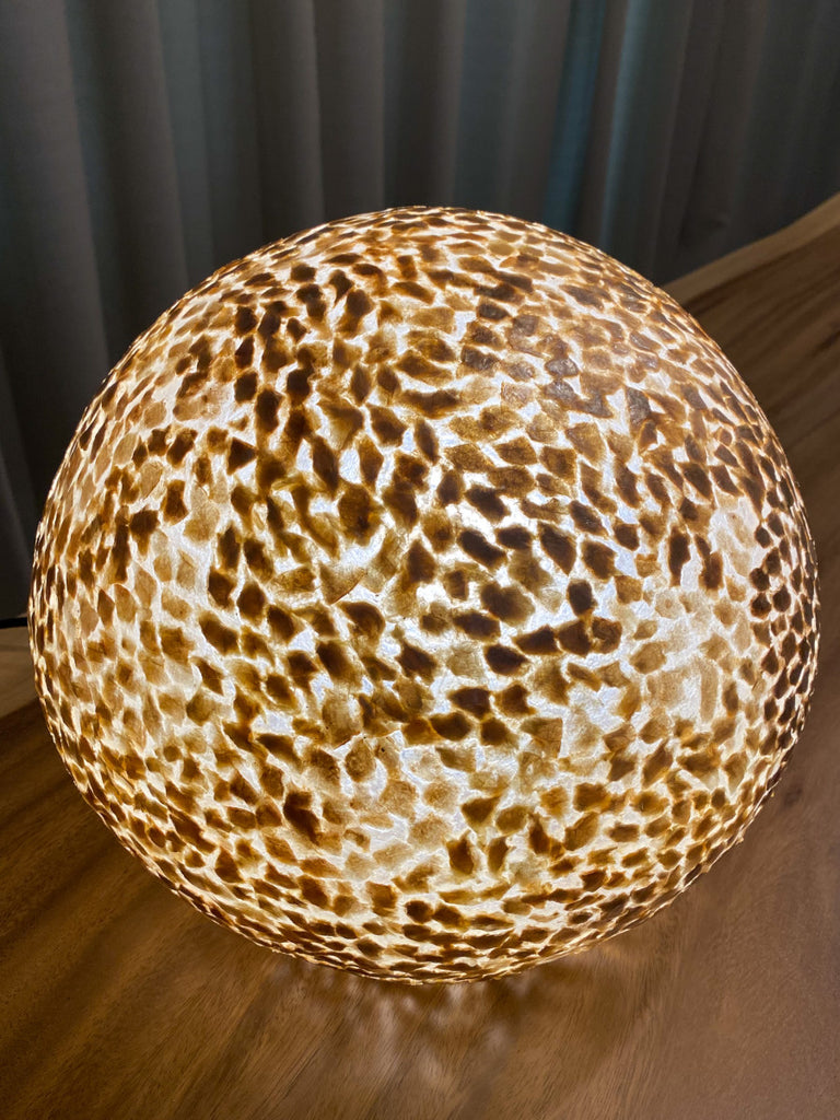 globe table lamp Wangi gold sphere standing on a cabinet in a living room in Singapore