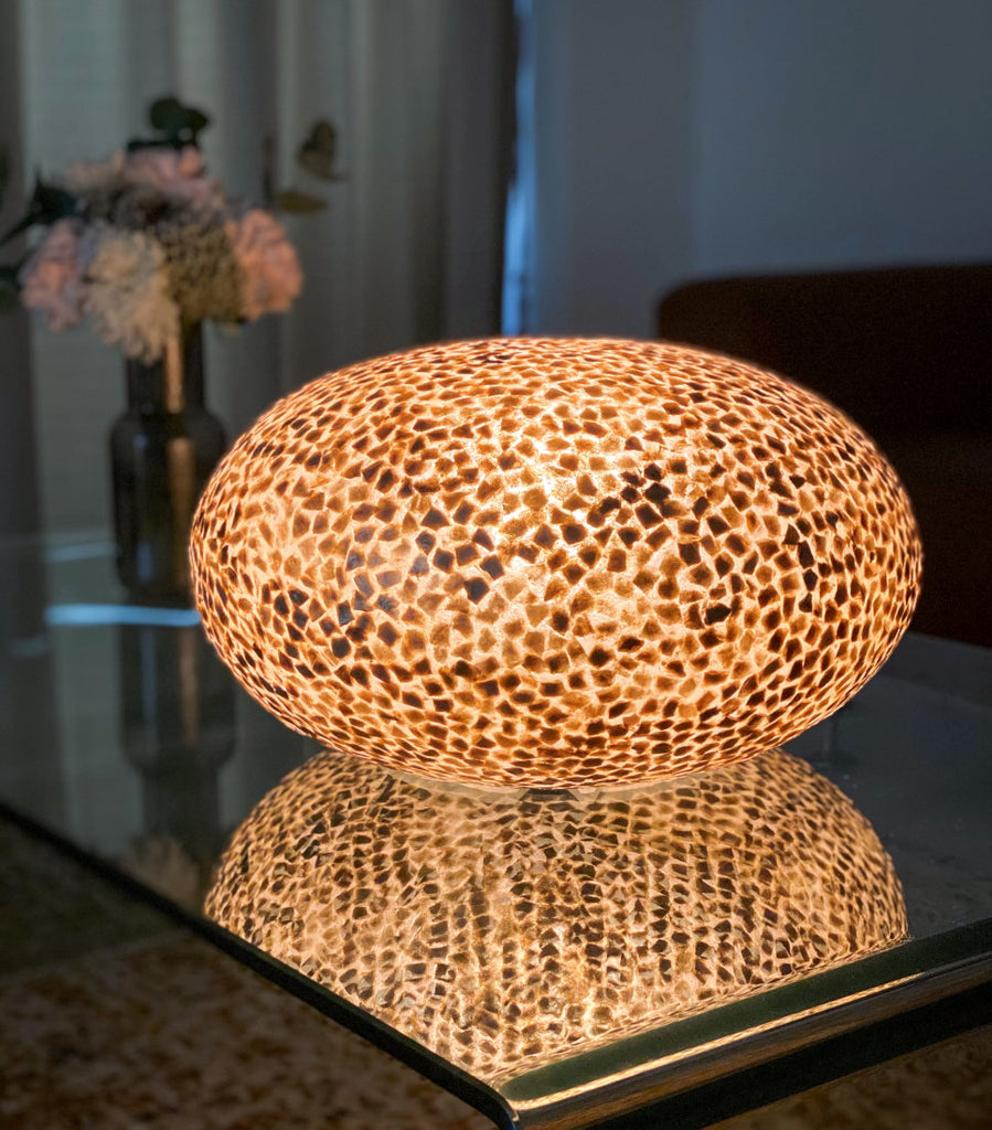 Wangi Gold Ufo Table Lamp in a living room. The illuminated Wangi Gold design is reflecting on a glass table in a condo in Singapore